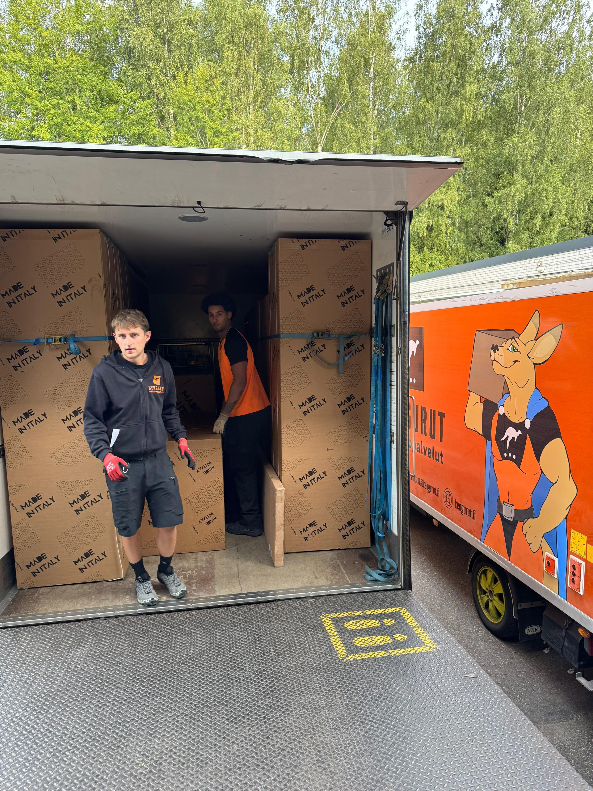 Muutto. Muuttomiehet kantamassa laatikoita.