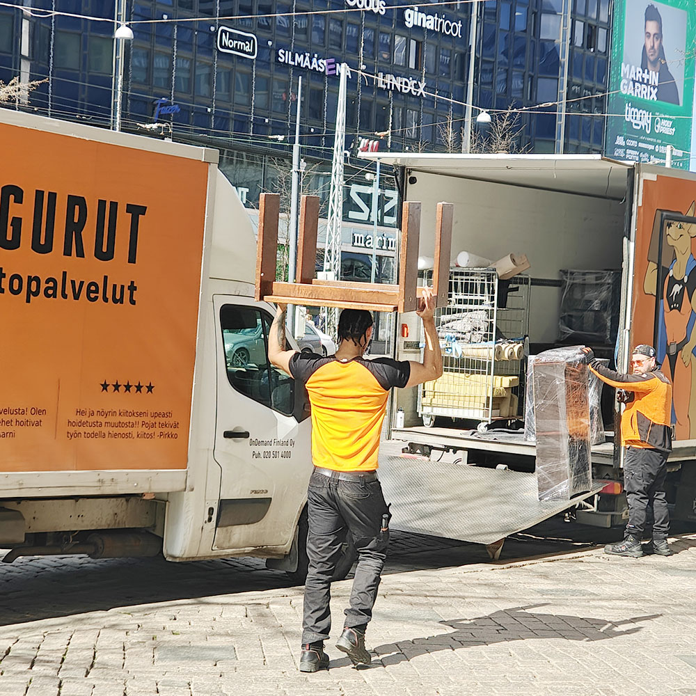 Muuttopalvelu Helsinki. Muuttomies kantaa päänsäpäällä pöytää kesken muuton Helsingin keskustassa.